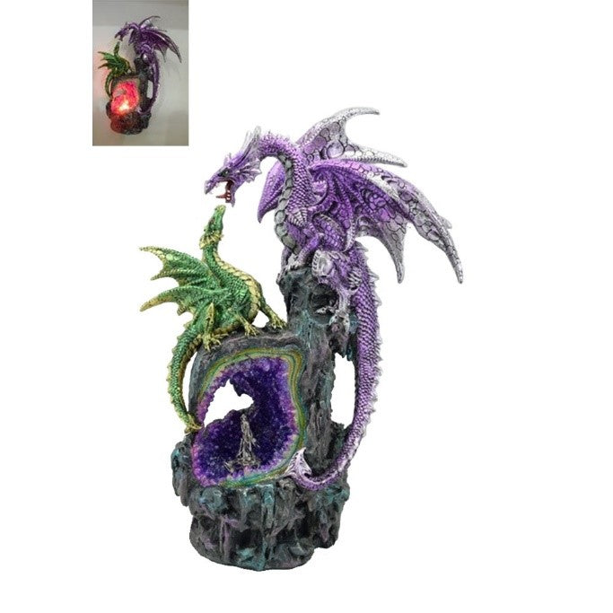 A statuette of a roaring purple dragon standing atop a craggy rockface, looking down at a young pale green dragon who is perched above the entrance of a cave lined with crystals.